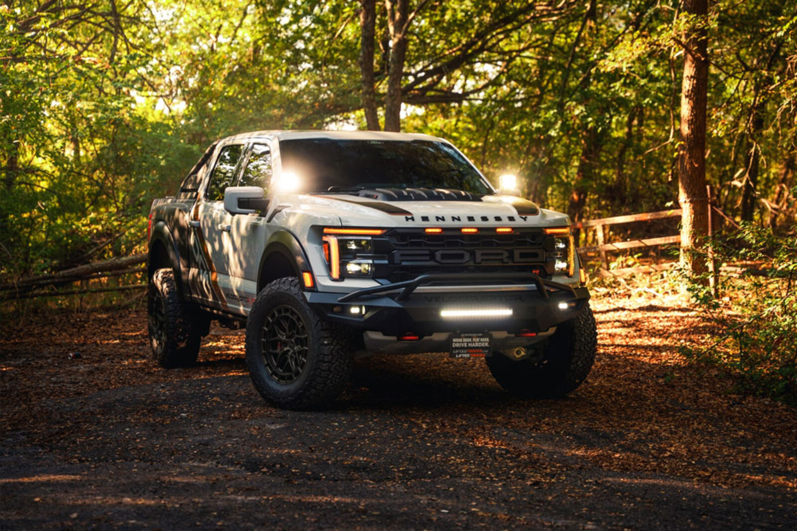 An off-road rig at blue hour, lights on, dust in the air